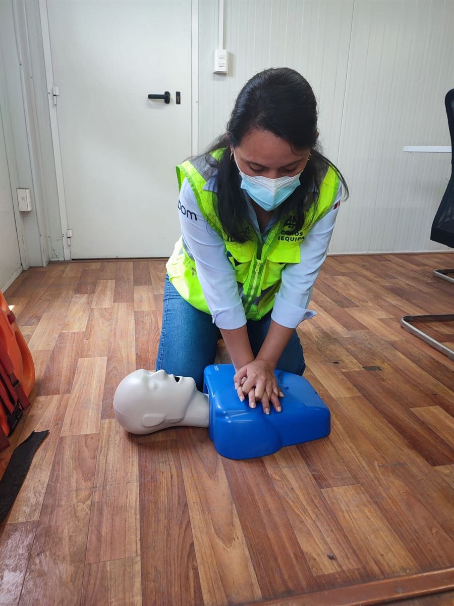 Participante practica reanimación cardiopulmonar con un maniquí de entrenamiento