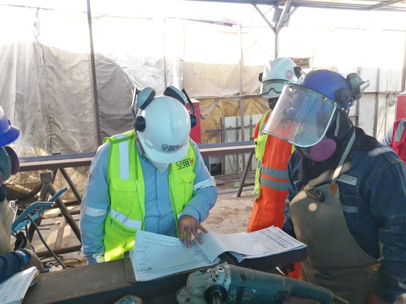 Consultor de SST revisa documentación con trabajadores en planta